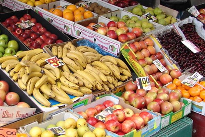 A fruit and vegetable stand with apples, bananas and mandarins.