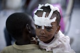 An injured girl is carried by her mother at a makeshift hospital on a street in Port-au-Prince