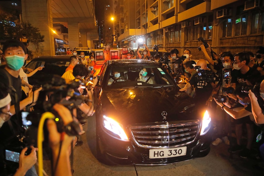 Hong Kong media tycoon Jimmy Lai gives a thumbs up as he sits in the front seat of a car surrounded by supporters.