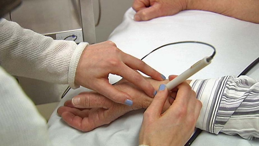 A Menzies Institute researcher uses a pen-like device to measure a patient's central blood pressure.