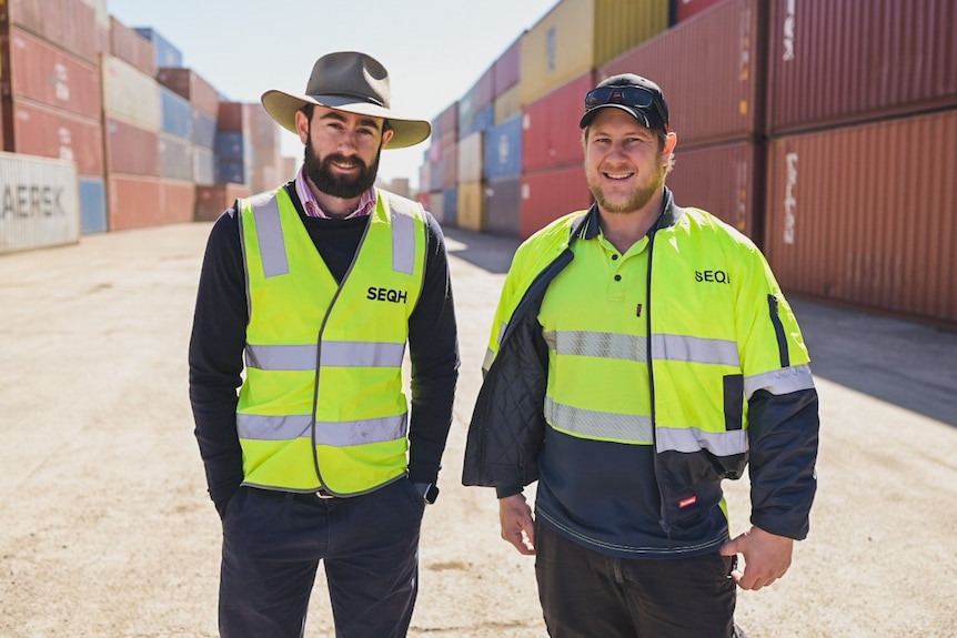 Two men standing in a shipping yard.