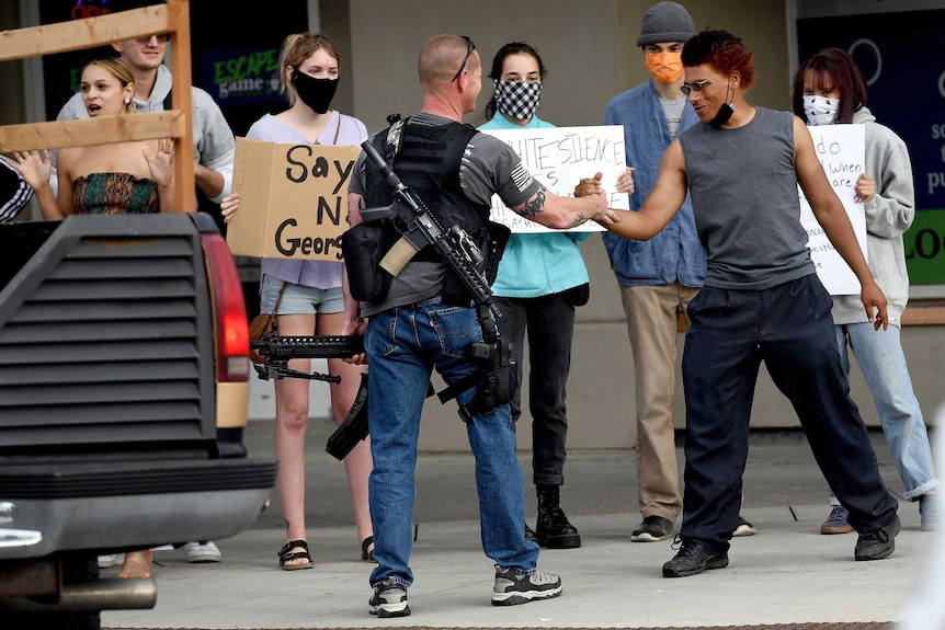 A heavily armed man shakes hands with a protester