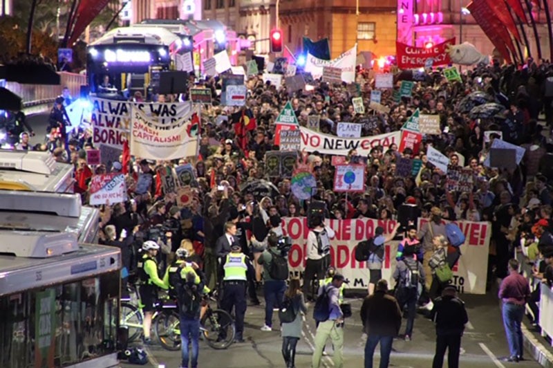 Hundreds of anti-Adani protesters march across Victoria Bridge in Brisbane CBD.