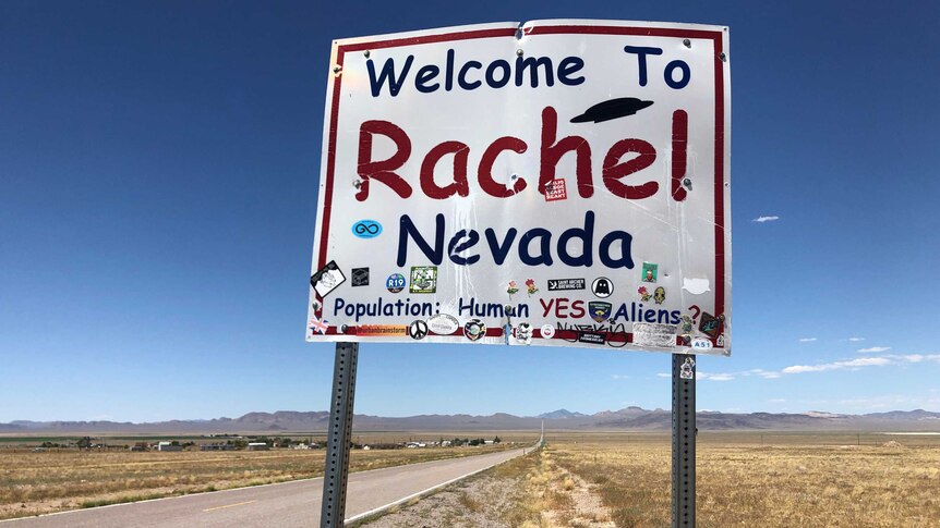 A sign reading "Welcome to Rachel Nevada" stands along the road in Rachel, Nevada, US