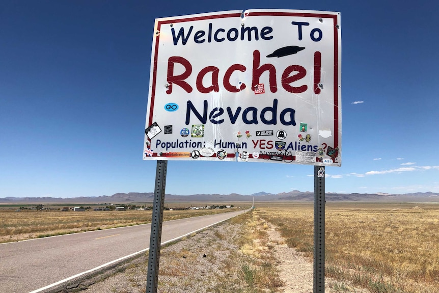 A sign reading "Welcome to Rachel Nevada" stands along the road in Rachel, Nevada, US