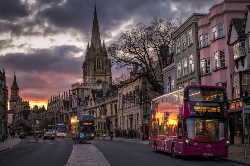 Buses line High Street, Oxford at sunset.