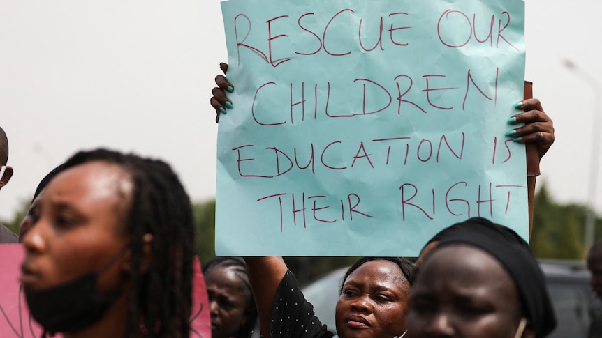 A parent holds up a sign saying "rescue our children education is their right" at a rally in Abuja, Nigeria