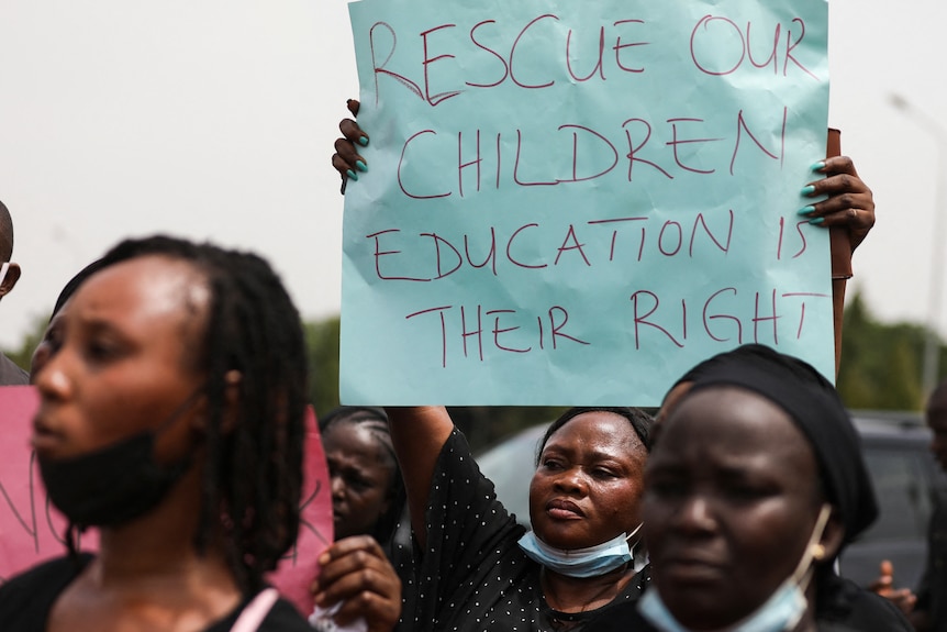 A parent holds up a sign saying "rescue our children education is their right" at a rally in Abuja, Nigeria