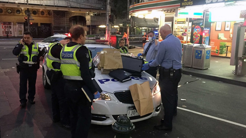 Police collect evidence on Elizabeth Street after two people were stabbed.