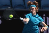 A headband-wearing tennis player's hair flies up as he swings at the ball for a forehand shot.