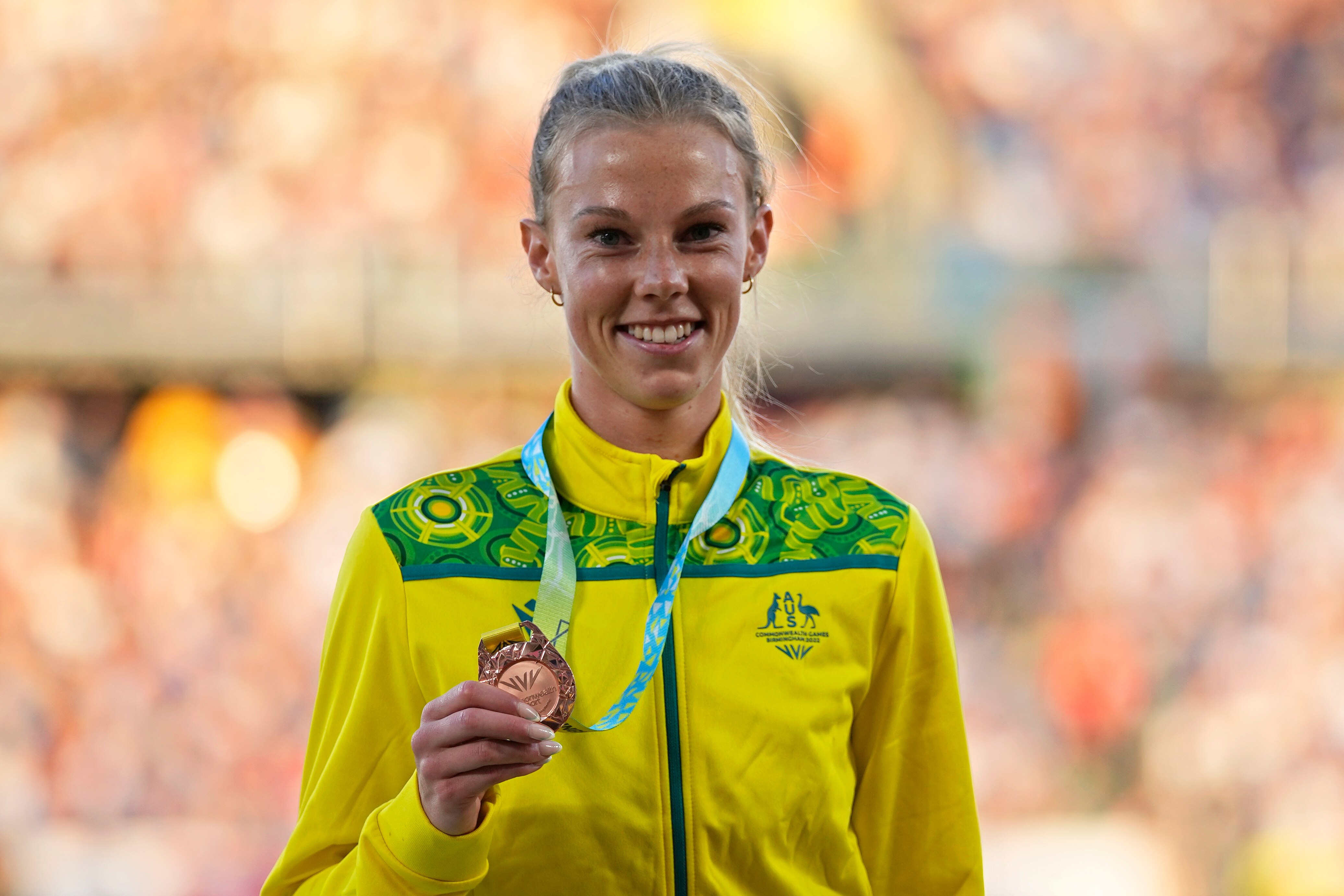 Australian runner Abbey Caldwell smiles as she stands on the podium with a bronze medal 