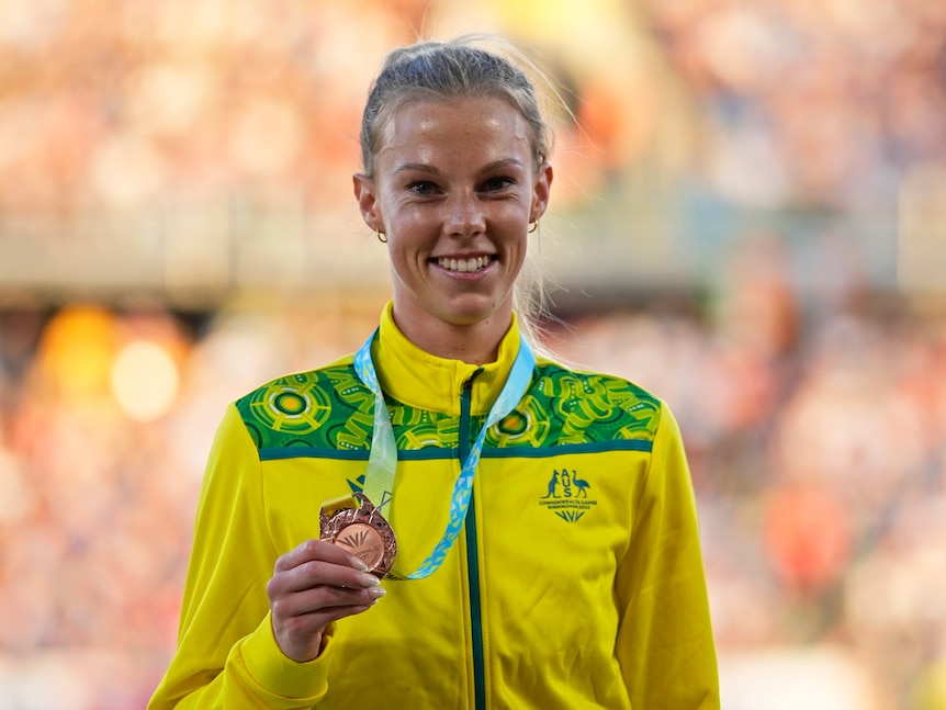Australian runner Abbey Caldwell smiles as she steps onto the podium with a bronze medal 