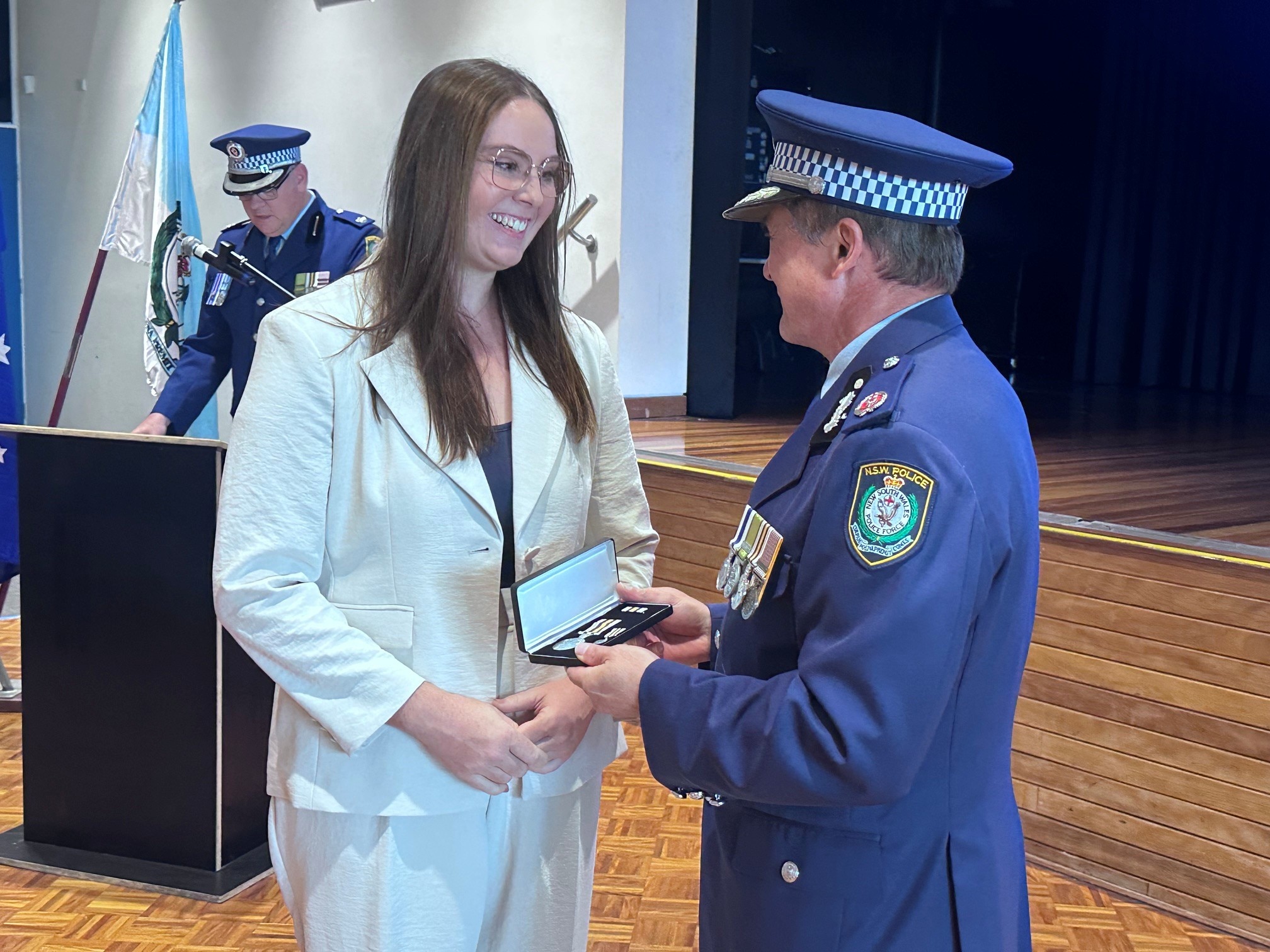 Woman standing receiving an award from a police officer