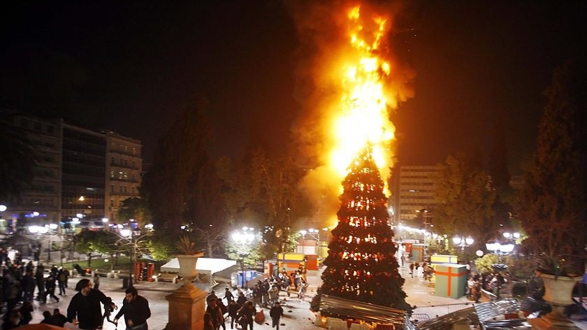 People flee from a burning Christmas Tree in Syntagma Square in Athens.