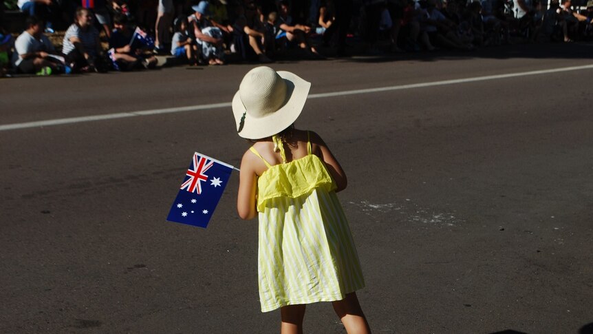 A girl in a yellow dress holds an Australian flag