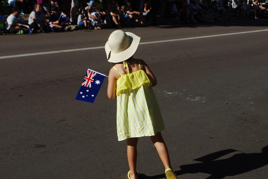 A girl in a yellow dress holds an Australian flag