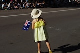 A girl in a yellow dress holds an Australian flag