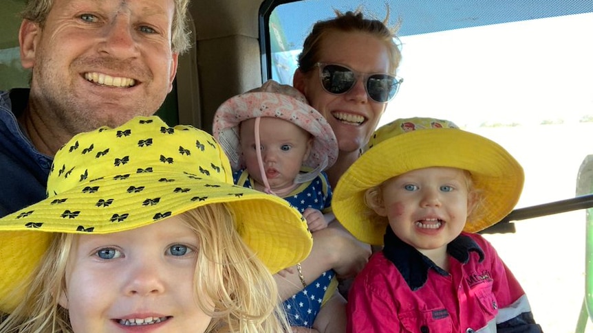 family of five in a tractor cab, three little girls smiling in big hats