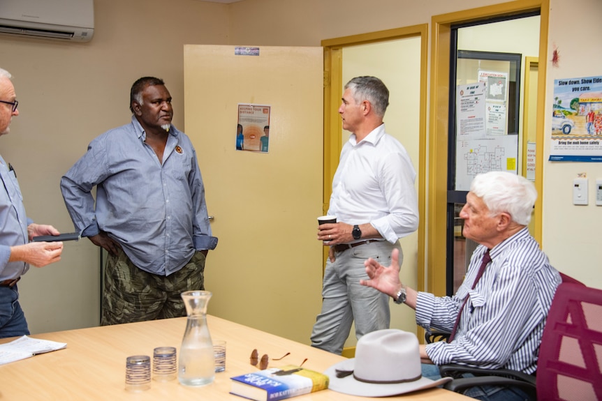 Bob Katter sits talking to Robbie Katter and Myron Johnny who are standing.