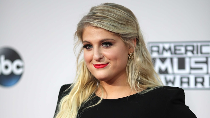 Singer Meghan Trainor smiles as she poses on a red carpet.