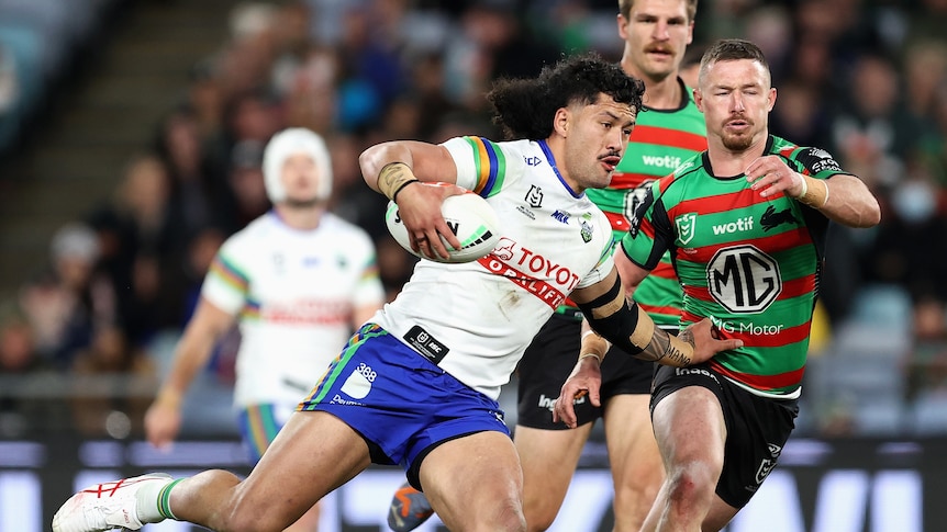 A man runs the ball during a rugby league 