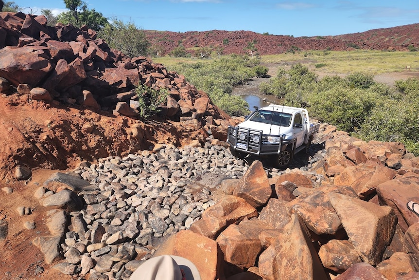 A four-wheel-drive treks up a very rocky hill.