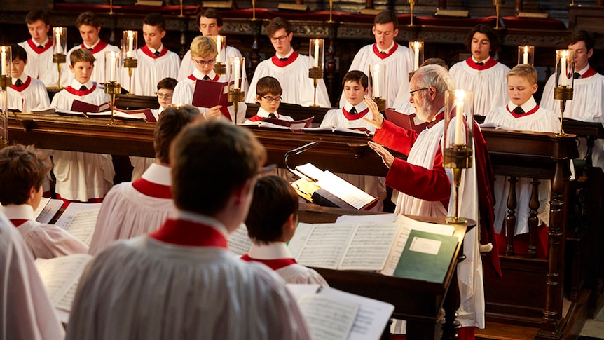 King's College Choir in performance in a church in white and red choir robes.