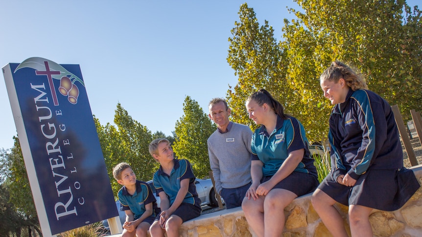 Gregg Smith with students at the entrance wall to Rivergum College.