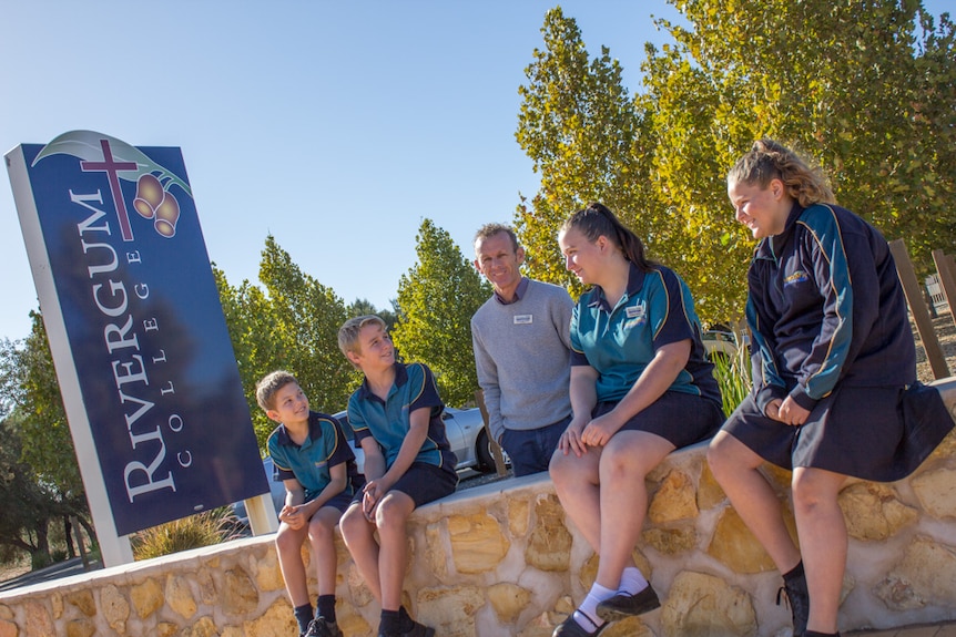 Gregg Smith with students at the entrance wall to Rivergum College.