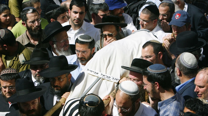 A shooting victim's body, wrapped in white funeral shrouds, is carried by friends in Jerusalem.