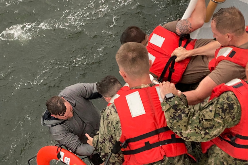 US Coast Guard crew members pull a man from the water after a commercial boat capsized off the coast of Louisiana.