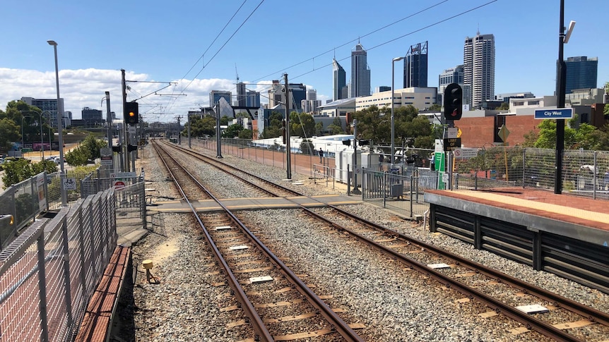 A train line stretches into the distance, the Perth skyline is visible.