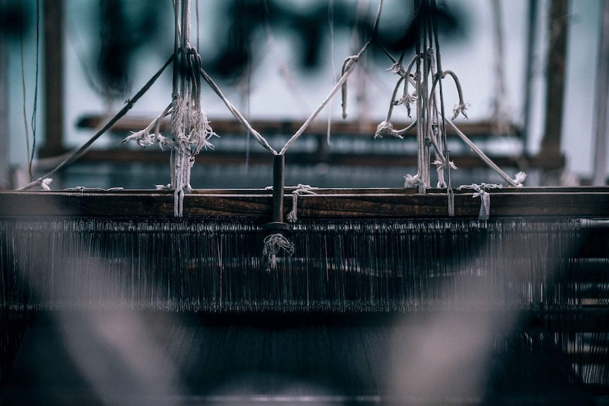 A wooden loom threaded with indigo yarn.