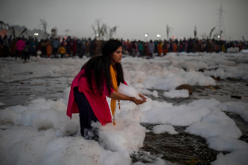 A Hindu devotee grabs a handful of toxic foam 