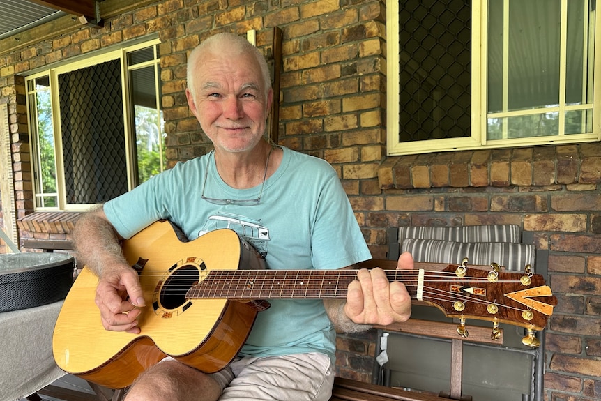 A man sits on a bench playing a guitar