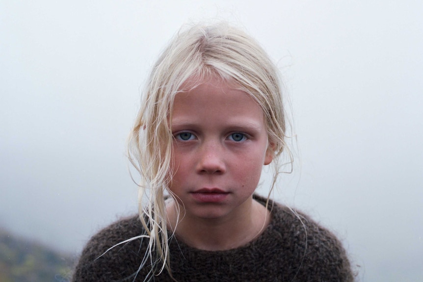 A young blonde girl standing in the fog in the film A White, White Day