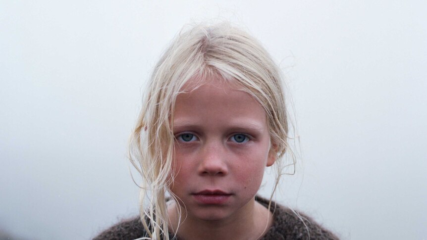 A young blonde girl standing in the fog in the film A White, White Day