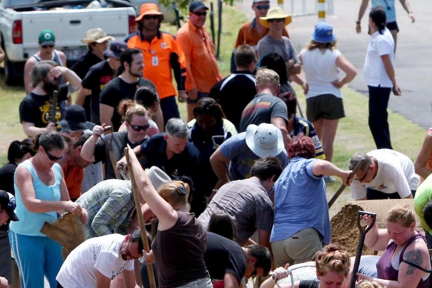 Residents fill and collect sandbags from a council supply drop in preparation for Cyclone Yasi