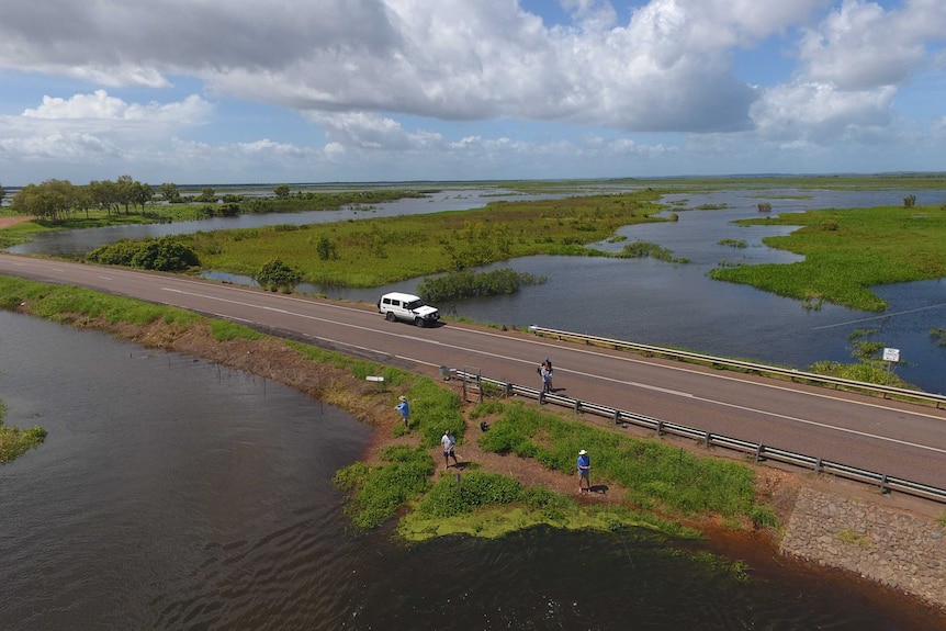 An aerial photo of people fishing off the Arnhem Highway with floodplains surrounding the road.