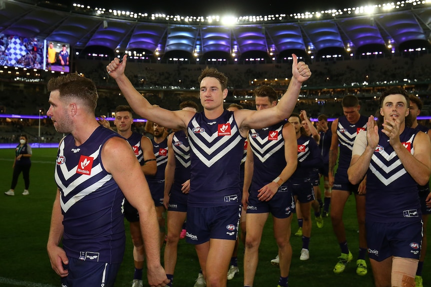 As dockers players leave the field Brennan Cox puts his hands in the air with his thumbs up 