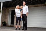 Fiona Fagan and Richard Sykes stand in front of their garage, Fiona is holding their son.