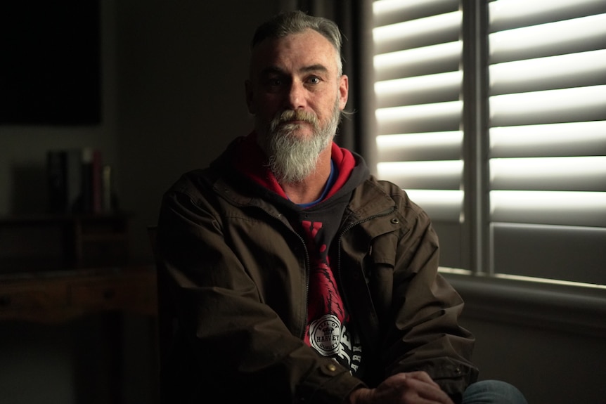 A man with a beard wears a green jacket.