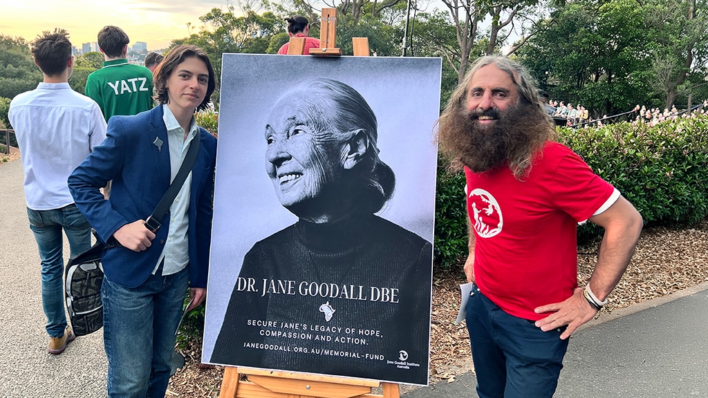 Costa and Spencer standing next to an easel with a picture of the late Jane Goodall.