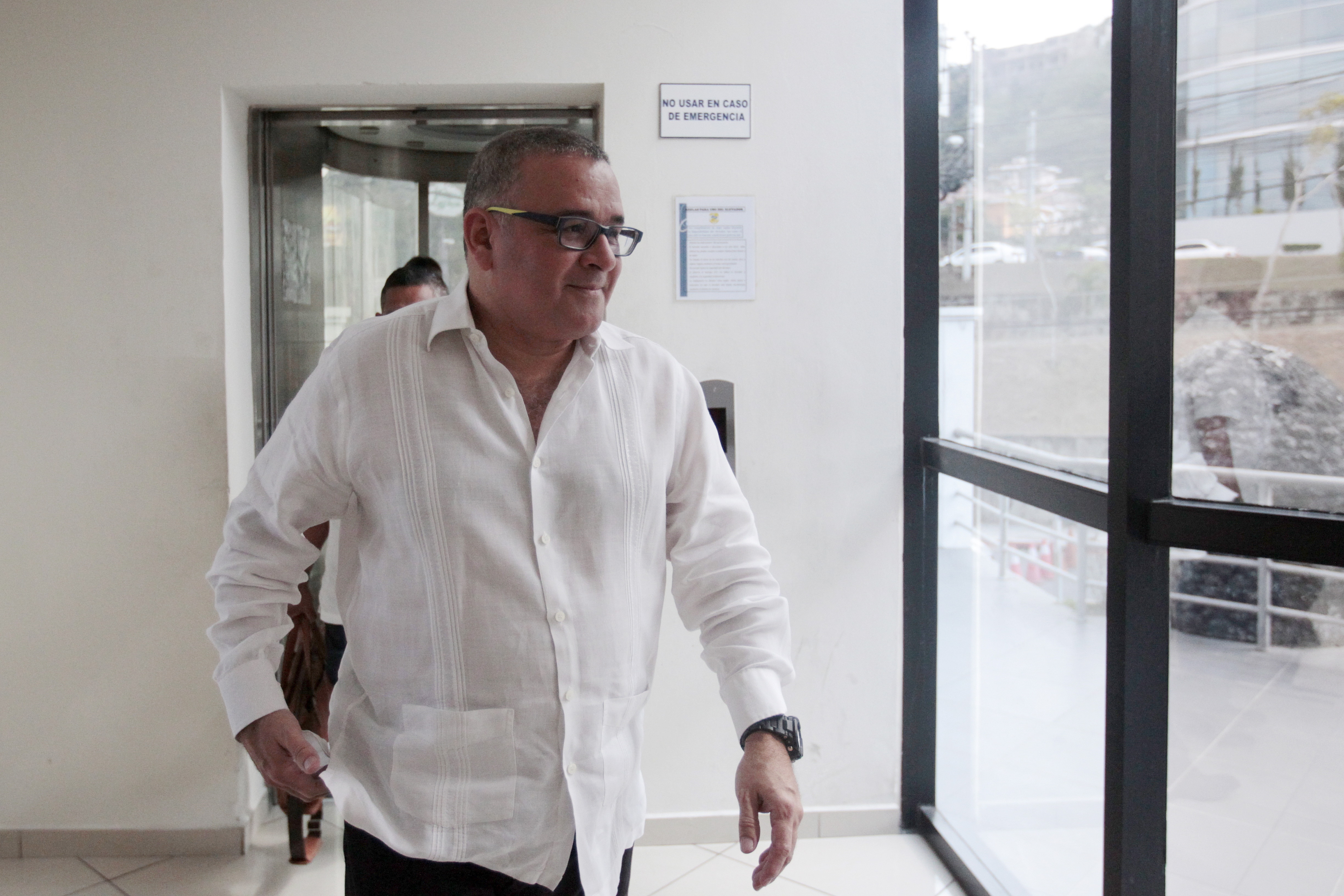 Maurcio Funes walking wearing a white button up shirt and glasses.