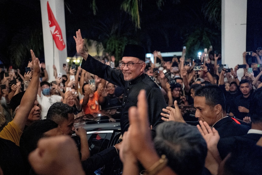 Anwar Ibrahim in a crowd of people, smiling and waving