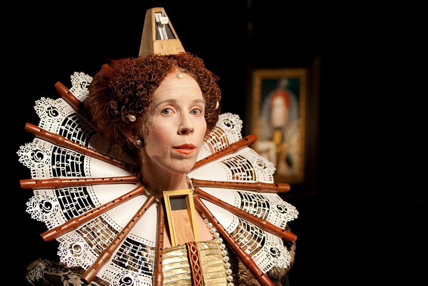 Recorder player Genevieve Lacey is dressed like Queen Elizabeth I, with a neck ruff made of recorders and a metronome hat