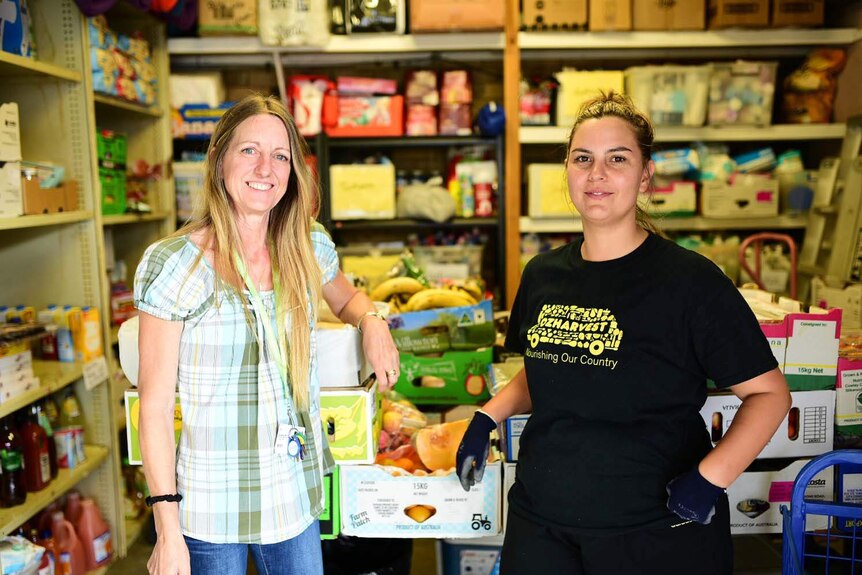 Penny Morris stands with Serra Caliskan surrounded by shelves of fresh food in a Brisbane warehouse.