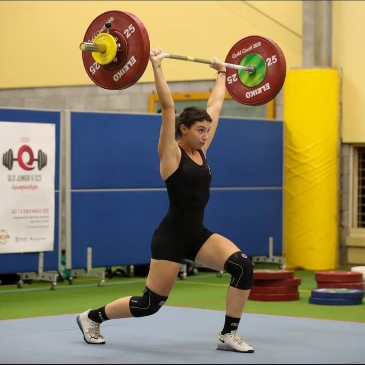 A woman in a black lycra weightlifter's suit lifts a bar with 25kg weights in each end.