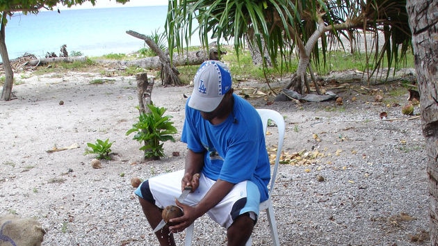 A Pacific islander chopping up coconuts