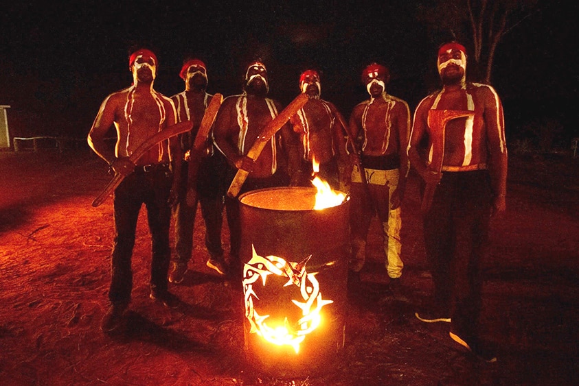 An image for Blacken Open Air festival of Indigenous people of Arrente Country gathered around a burning oil drum at night